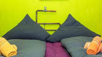 Ein Bett mit zwei Kissen, einer violetten Matratze und auf beiden Seiten gerollten Handtüchern.
