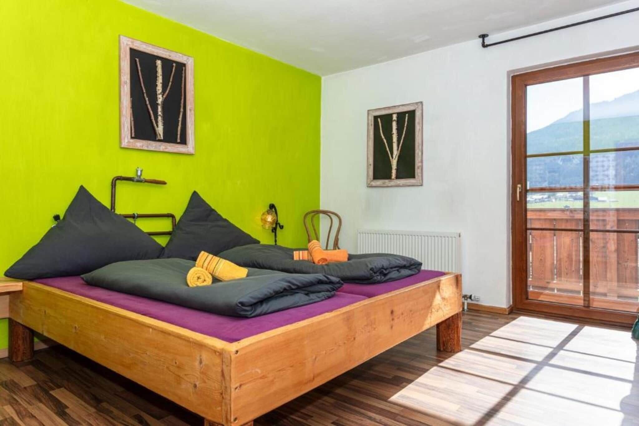 A room with a wooden bed, green walls, and a view through a sliding door.