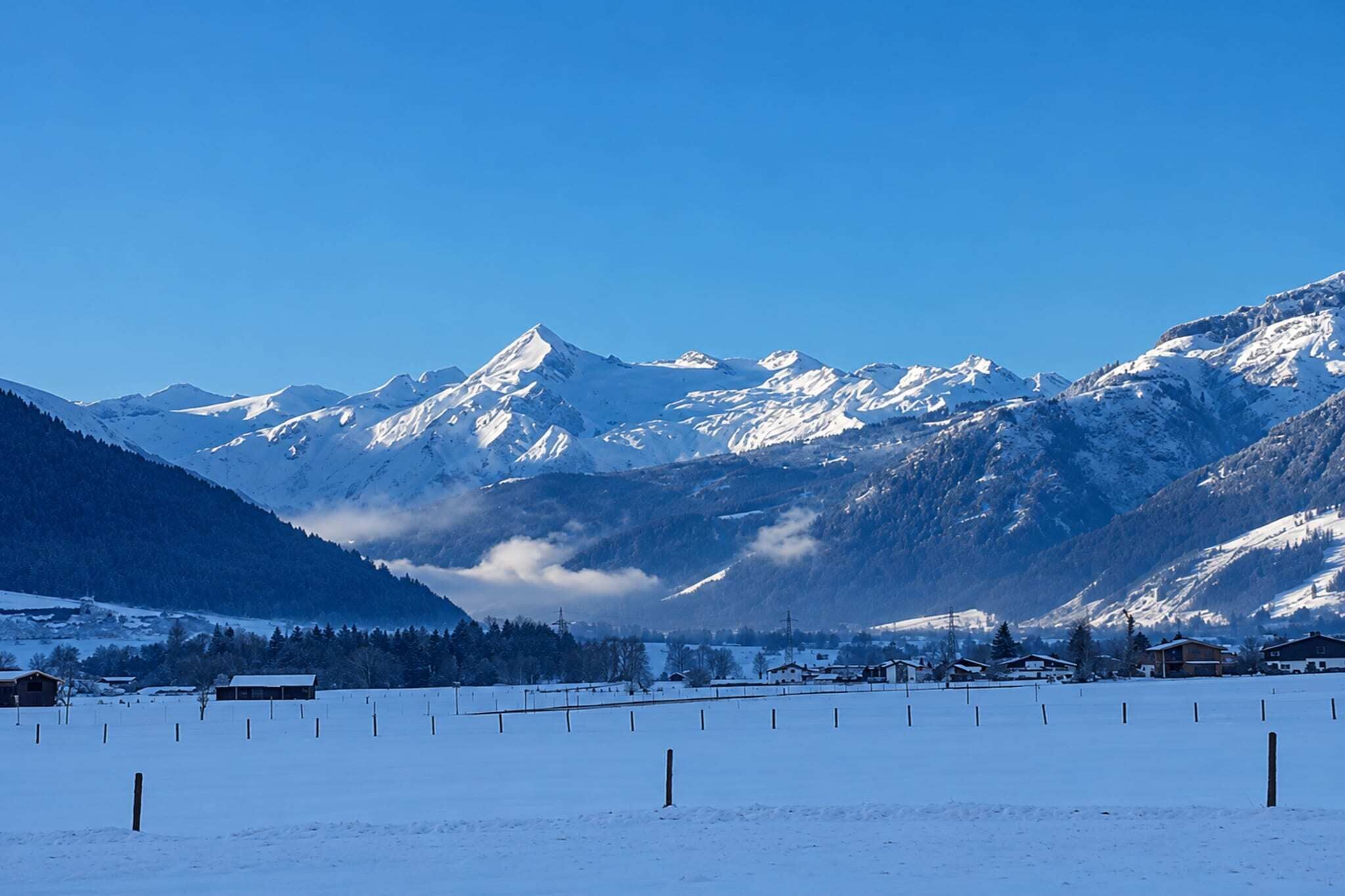 A snow-covered landscape with mountains in the background and a clear sky.