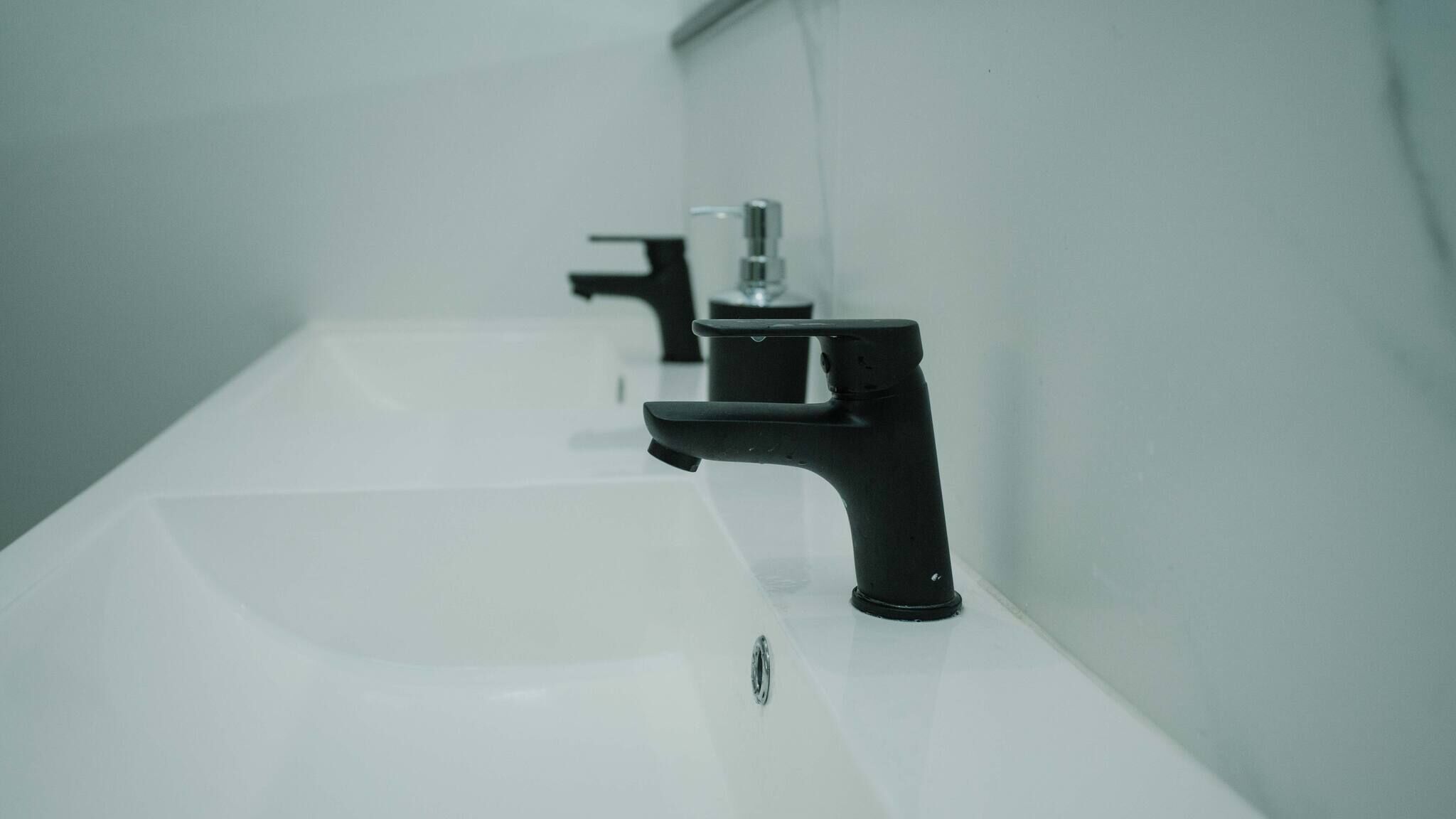 Une salle de bain avec un lavabo blanc et un robinet noir.