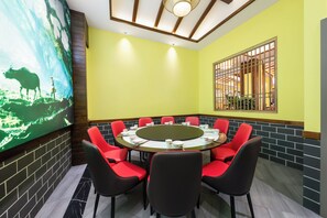 Una sala conferenze con un tavolo rotondo, sedie rosse e un grande quadro appeso al muro.