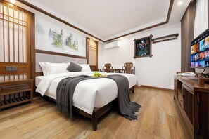 Una habitación de hotel con cama, mesitas de noche, escritorio y televisión.