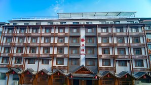 A multi-story hotel with a central vertical sign, balconies, and a symmetrical facade. - HuaHarmony Wulingyuan City Inn (Zhangjiajie)