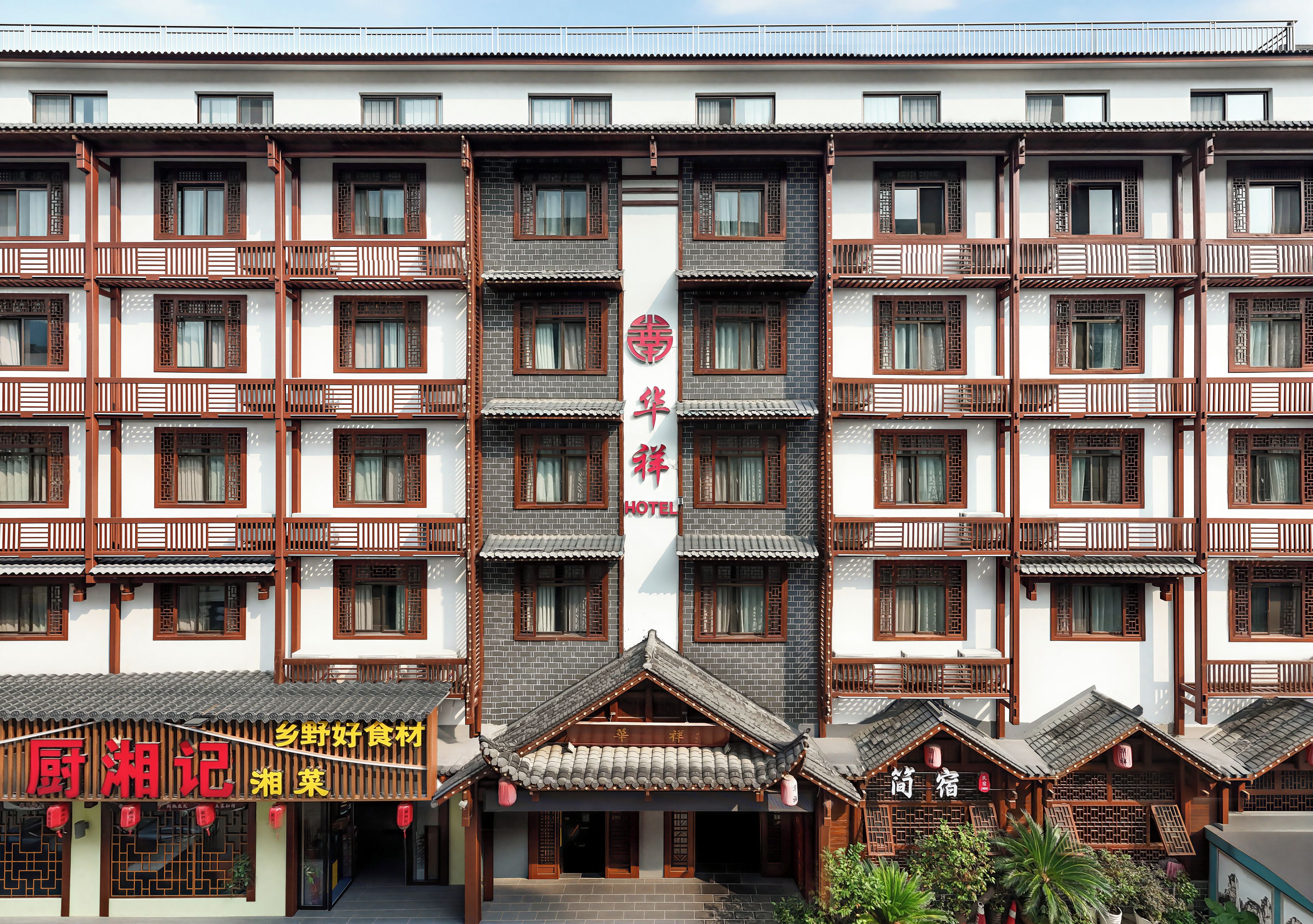 Un immeuble à plusieurs étages présentant des éléments d’architecture chinoise traditionnelle, notamment des toits couverts de tuiles et des fenêtres à croisillons en bois.