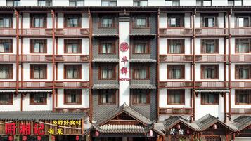 Un immeuble à plusieurs étages présentant des éléments d’architecture chinoise traditionnelle, notamment des toits couverts de tuiles et des fenêtres à croisillons en bois.