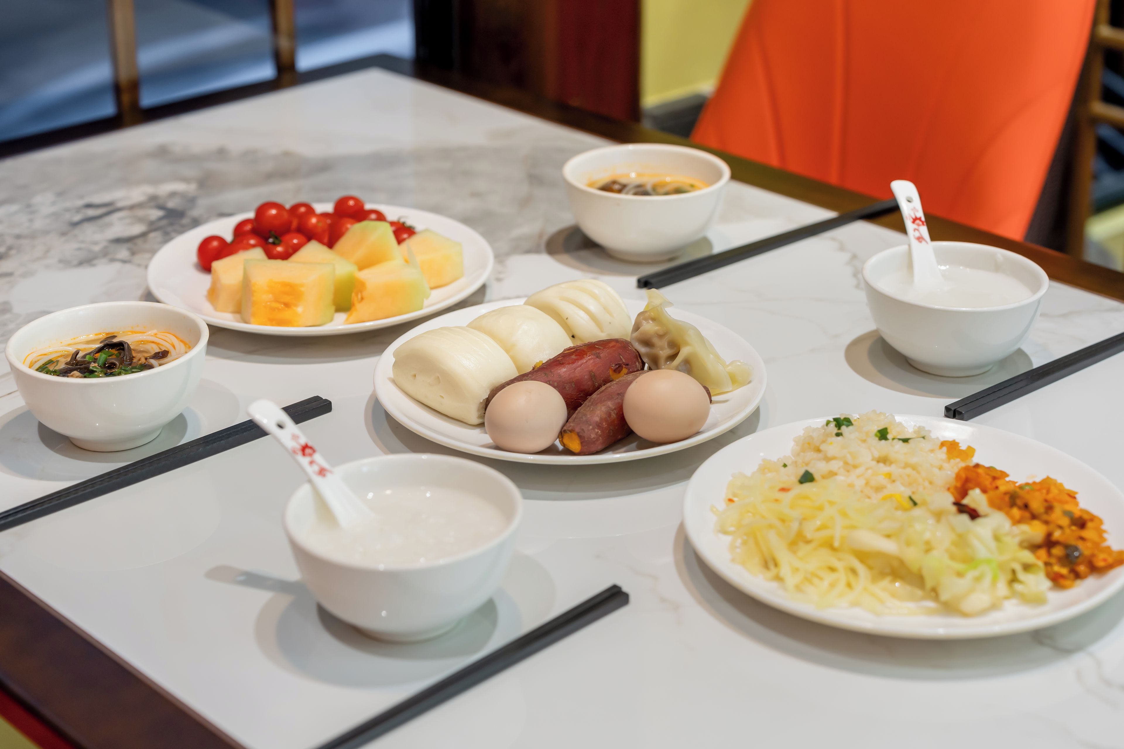 Une table garnie de différents plats, notamment une assiette de raviolis, un bol de soupe et une assiette de légumes.