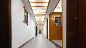 A long, narrow hallway with a series of doors on one side and a wooden wall on the other, featuring framed artwork. - HuaHarmony Wulingyuan City Inn (Zhangjiajie)