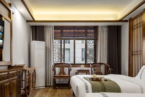 Quarto de hotel com cama, escrivaninha, cadeira, guarda-roupa e janela com cortinas.