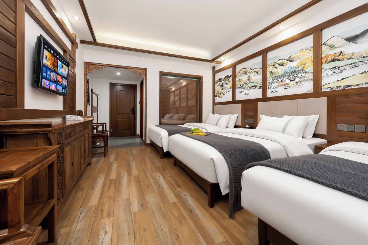 Quarto de hotel com piso de madeira, TV na parede e obras de arte nas paredes.