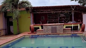 Une piscine dotée d’un bar et d’une terrasse dallée de pierres.