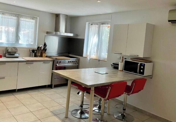 A compact kitchen with a dining table and chairs, a microwave, and a stove. - House in Porto Vecchio (Porto-Vecchio)
