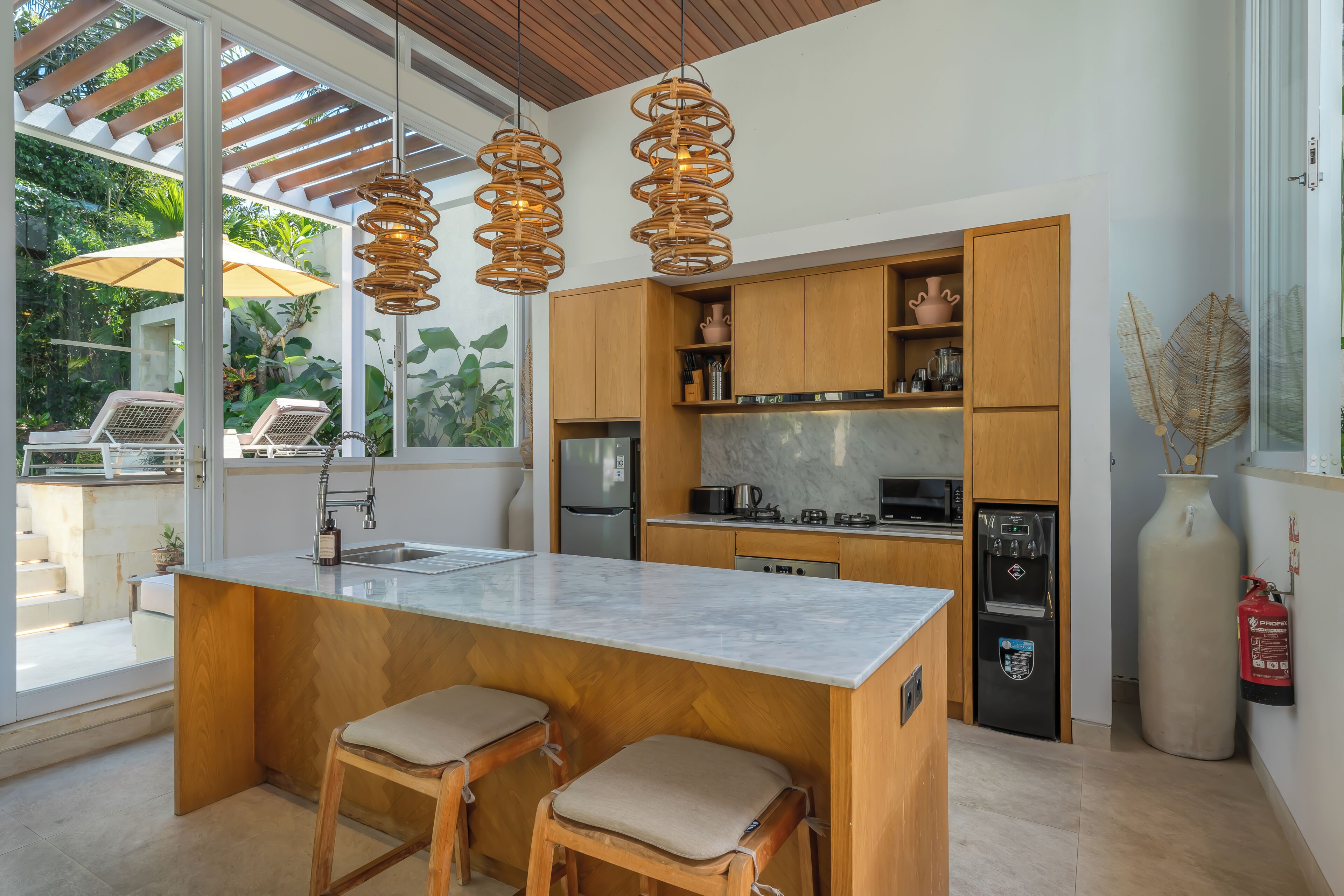 Una cocina moderna con una isla grande, armarios de madera y un refrigerador empotrado.