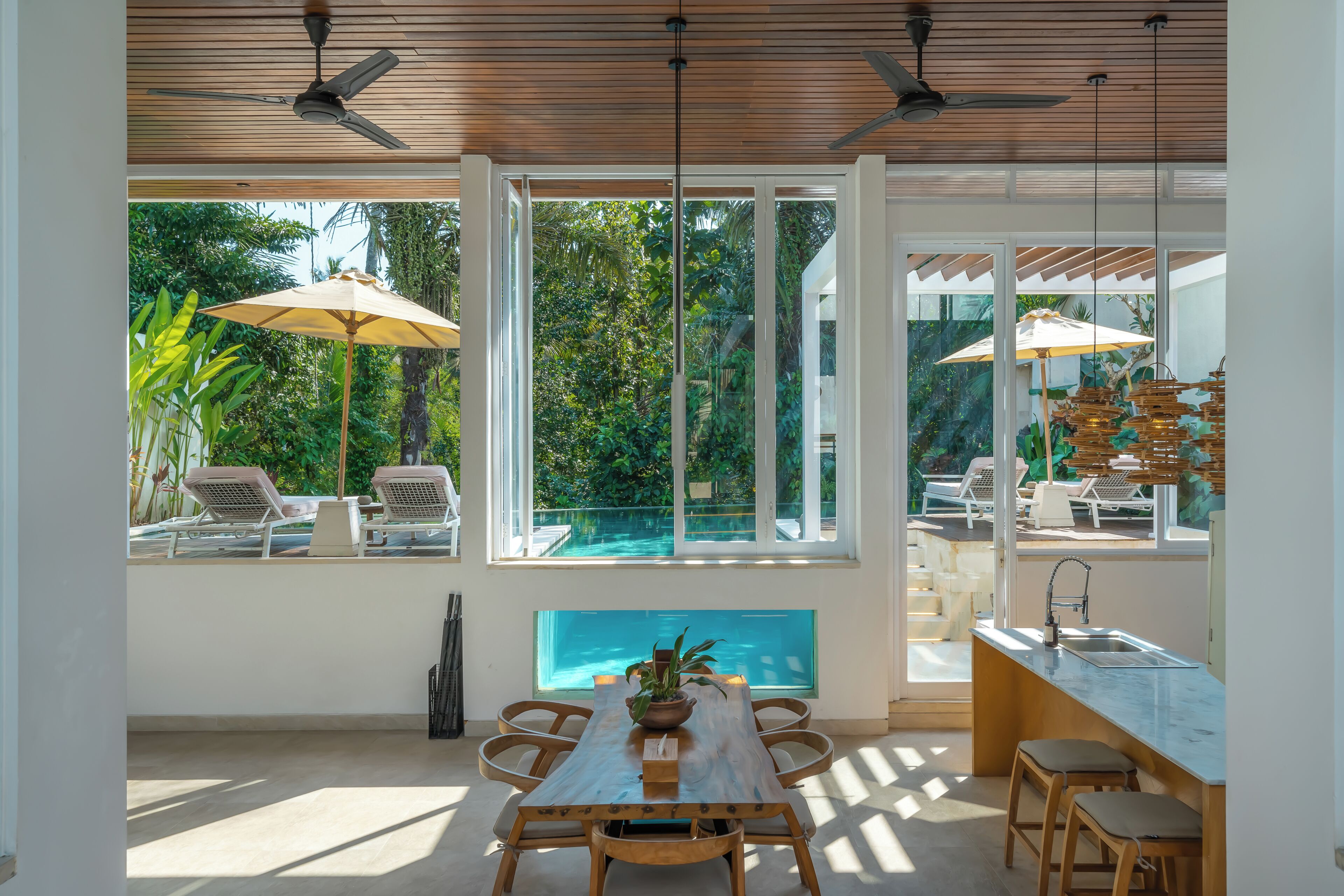 Un interior moderno con comedor, cocina y vistas a una piscina al aire libre.
