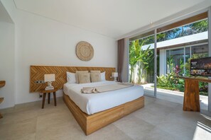 Una habitación de hotel moderna con una cama grande, cabecera de madera, mesita de noche con lámpara y vistas al exterior a través de amplias ventanas.