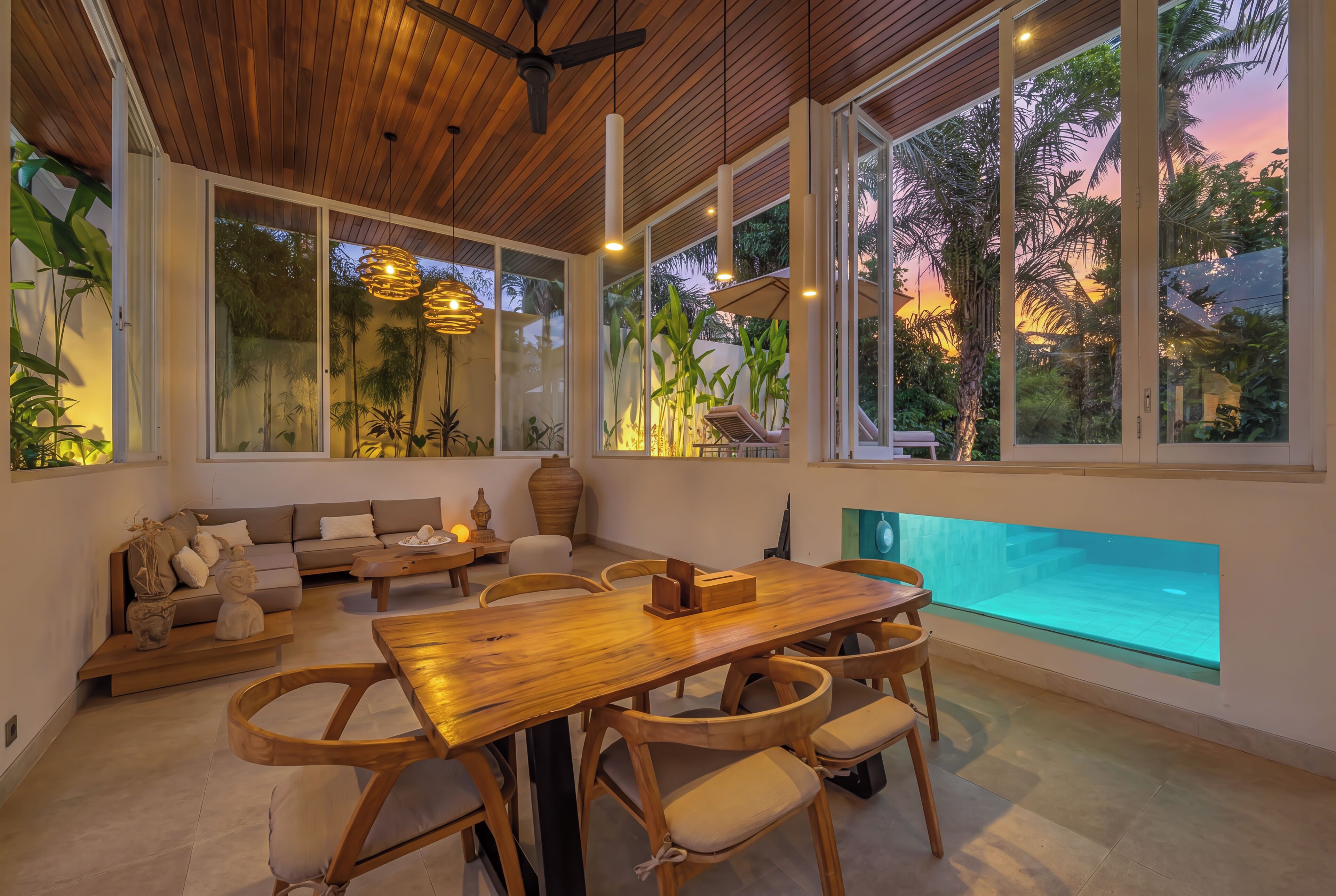 Un interior moderno con techo de madera, ventanas amplias, piscina y comedor.
