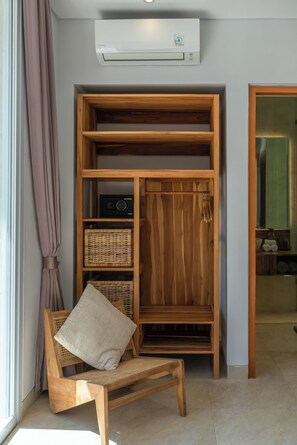 Ein Holzkabinent mit Regalen, ein Korbstuhl und eine Wand-Klimaanlage.