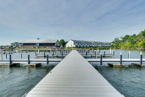 Ein Hotel am Wasserufer mit einer langen Anlegestelle, die sich in ruhiges Wasser erstreckt, umgeben von viel Grün.