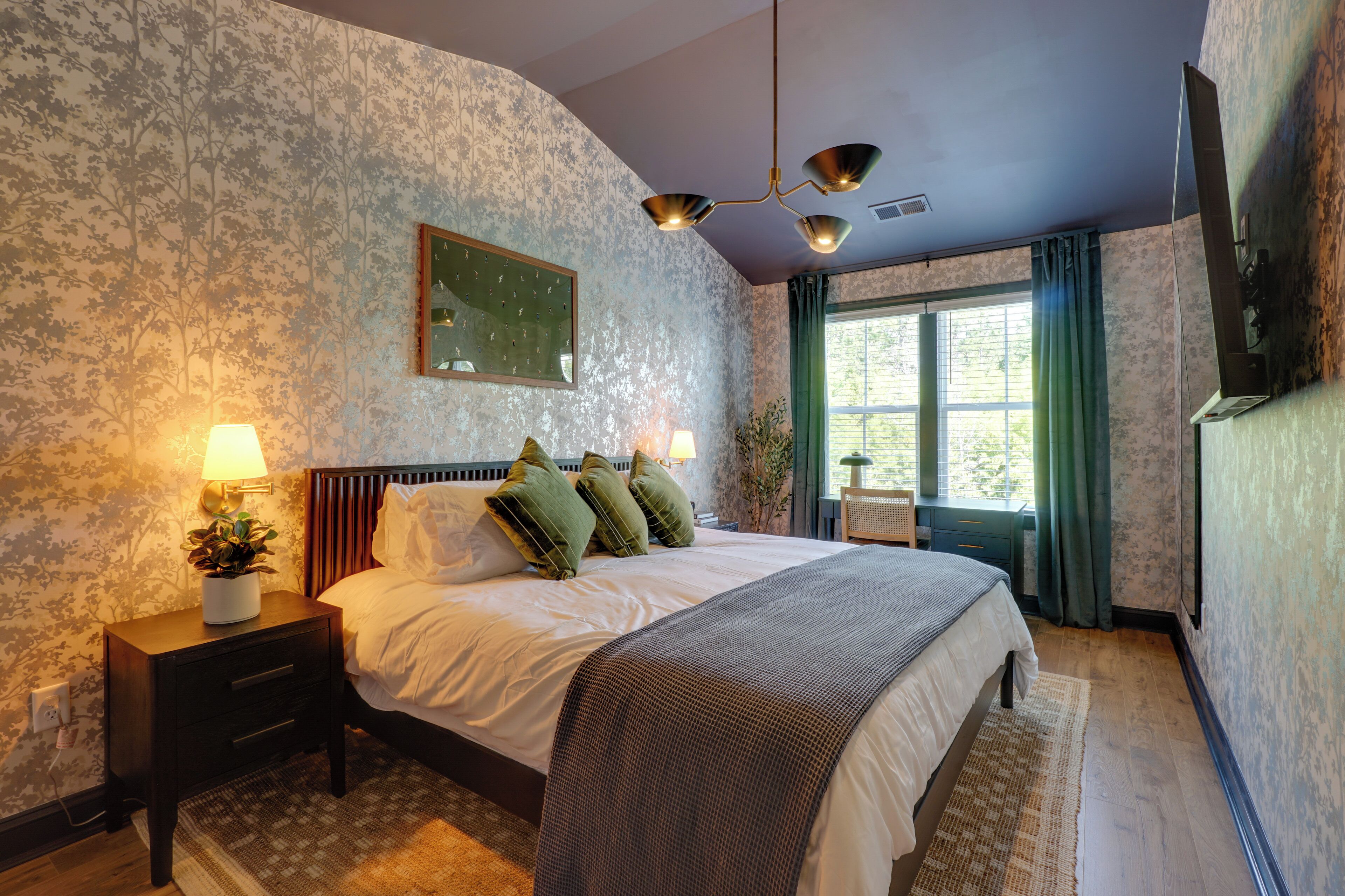 A bedroom with a bed, nightstands, a mirror, a window with curtains, and a ceiling fan.