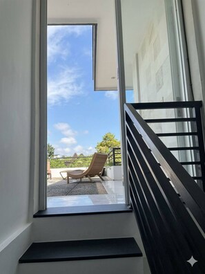 A modern interior with a staircase leading to a balcony. - 3 BR, 250 Sqmt villa, Terrace, 10 min Finns (Kecamatan Kuta Utara)