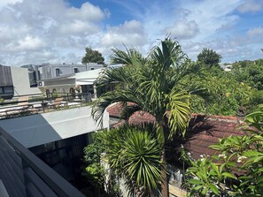 Eine Dachterrasse mit Blick auf ein modernes Gebäude, umgeben von üppiger Vegetation und einem klaren Himmel.