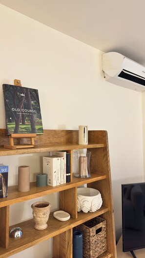 Puinen hylly, jossa on kirjoja, kynttilöitä ja koriste-esineitä.