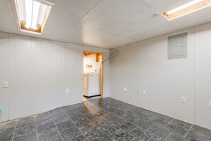 Une pièce dotée d’un sol carrelé, d’une prise électrique visible et d’une porte donnant sur une autre pièce.