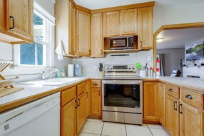 Une cuisine avec des meubles de rangement en bois, un four à micro-ondes, un four traditionnel et un lave-vaisselle.