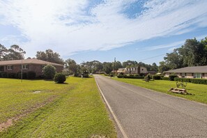 A residential street with houses on both sides, a clear sky, and a well-maintained lawn.