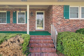 A brick building with a front porch, a door, and a small set of steps leading to the entrance.