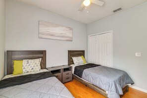 A bedroom with two beds, a nightstand, a ceiling fan, and a door. - Swim, Golf & Park-Hop! Family Home in Davenport (Davenport)