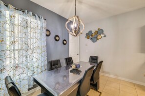 A dining area with a marble table, black chairs, a chandelier, and wall decor. - Swim, Golf & Park-Hop! Family Home in Davenport (Davenport)