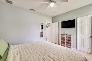 A bedroom with a bed, a ceiling fan, a TV mounted on the wall, and a dresser with drawers. - Swim, Golf & Park-Hop! Family Home in Davenport (Davenport)