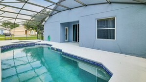 A swimming pool with a clear blue water, surrounded by a covered patio area with a metal roof structure. - Swim, Golf & Park-Hop! Family Home in Davenport (Davenport)