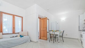Ein kompakter Wohnbereich mit einer Couch, Esstisch, Stühlen und einer Küchenzeile.