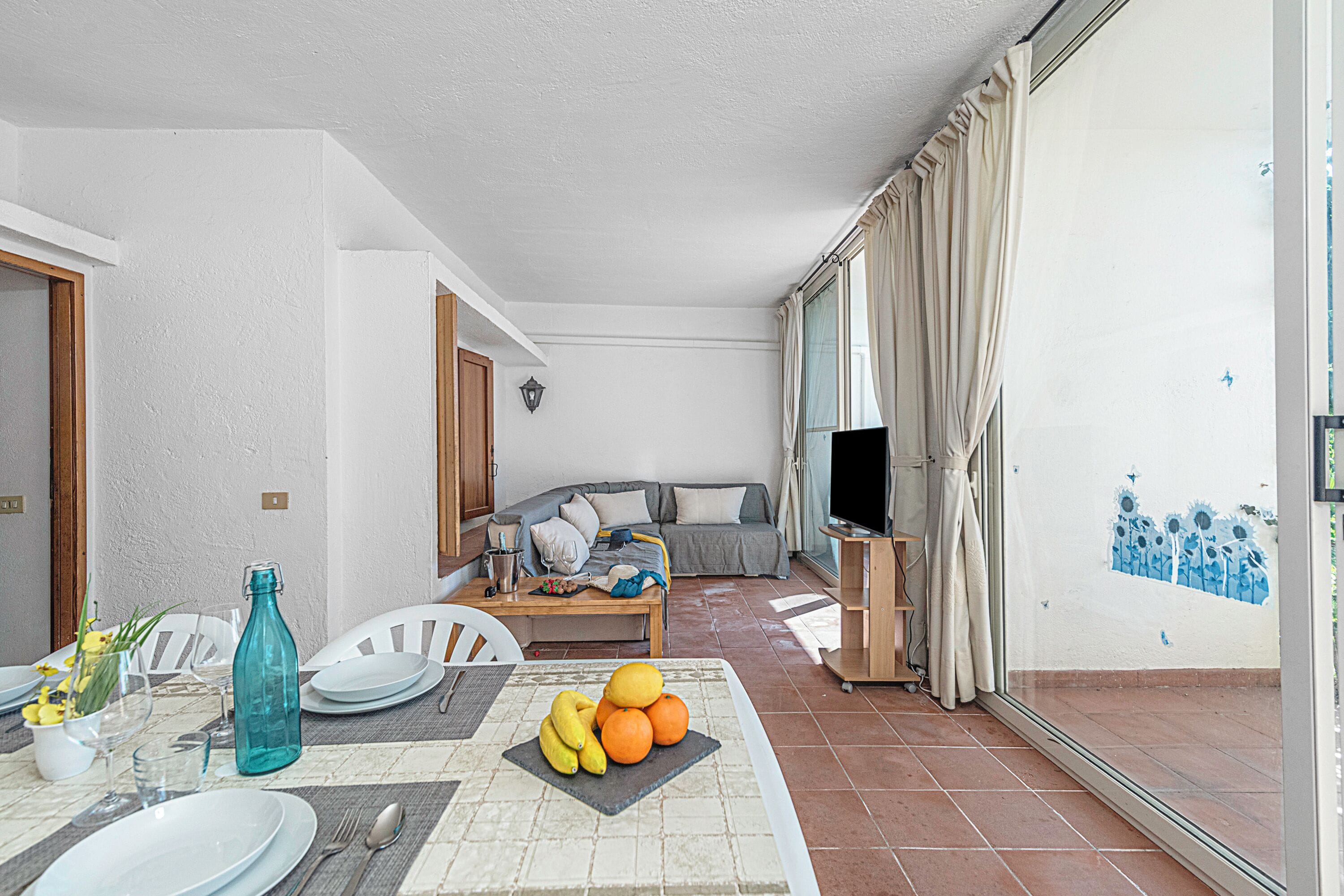 Ein Wohnzimmer mit Sofa, Fernseher und Essbereich mit Tisch für zwei Personen.