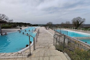 A swimming pool area with multiple pools, a wooden deck, and a view of the surrounding landscape. - Charming Tuscan Stone Farmhouse Retreat for Two (Rapolano Terme)