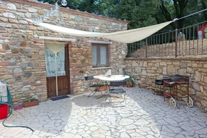 A stone building with a door, a window, a table with chairs, and a small cart. - Charming Tuscan Stone Farmhouse Retreat for Two (Rapolano Terme)