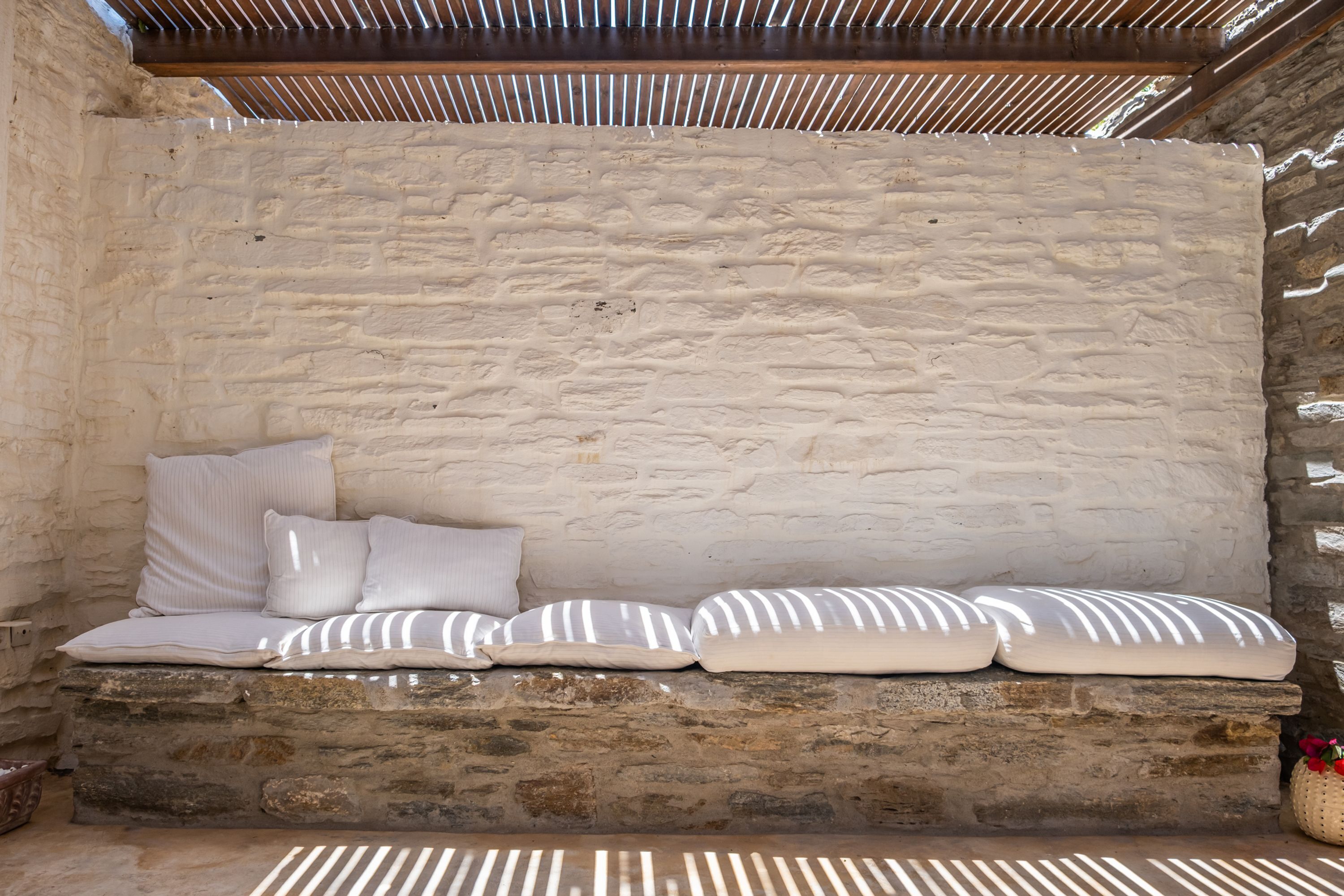 A stone bench with cushions against a textured wall.