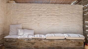 A stone bench with cushions against a textured wall.