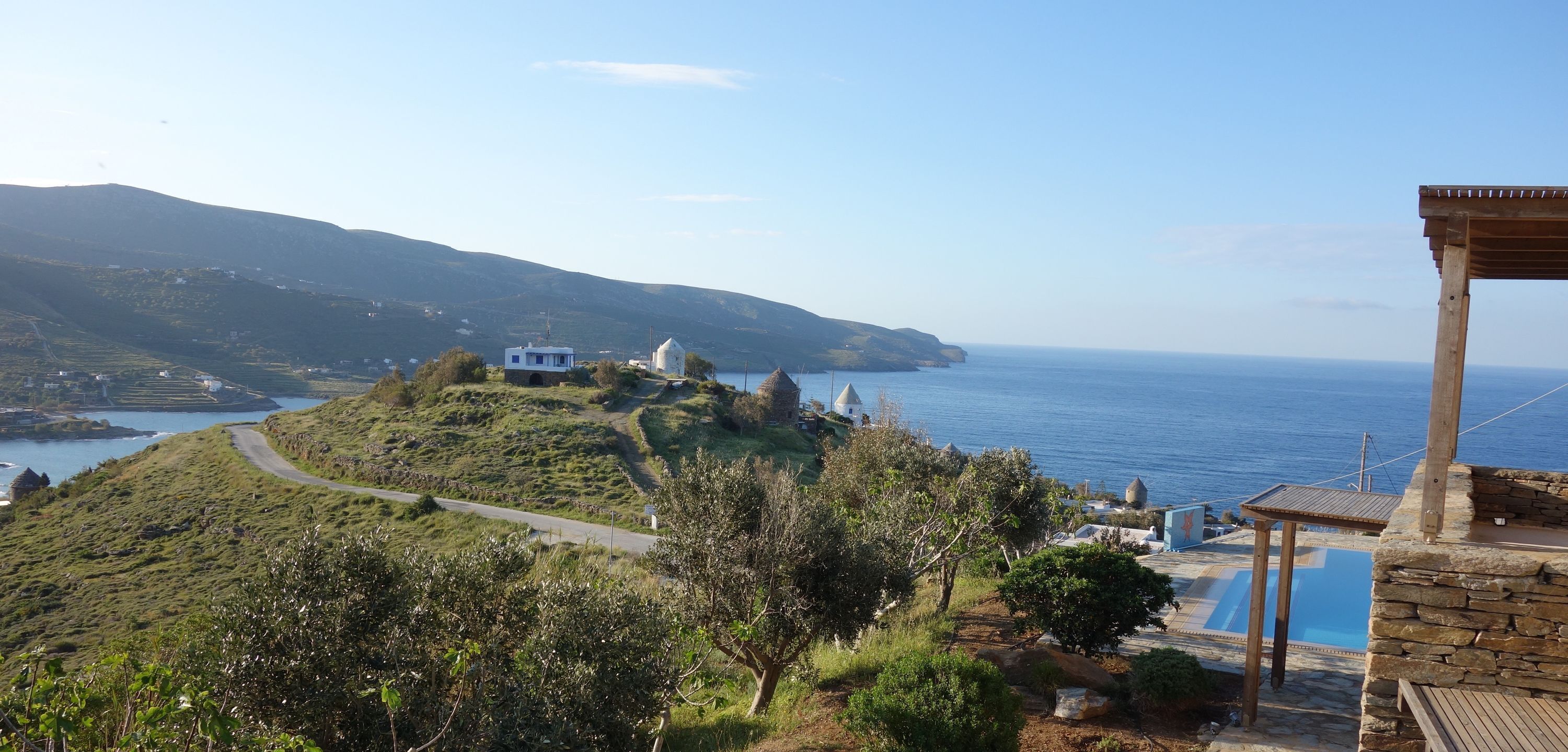 A coastal view with a road leading to a white building, a pool area, and a view of the sea.
