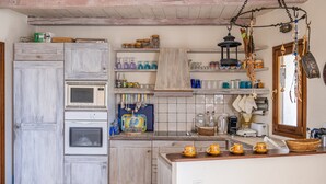A kitchen with wooden cabinets, a microwave, a kettle, and various kitchen utensils. - Zephyros Pool Tennis (Kea)
