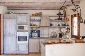 A kitchen with wooden cabinets, a microwave, a kettle, and various kitchen utensils. - Zephyros Pool Tennis (Kea)