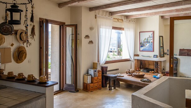 A rustic kitchen with wooden beams, a large window, and various kitchen items. - Zephyros Pool Tennis (Kea)
