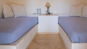 A room with two beds, a nightstand, a lamp, and a wall-mounted light fixture. - Zephyros Pool Tennis (Kea)