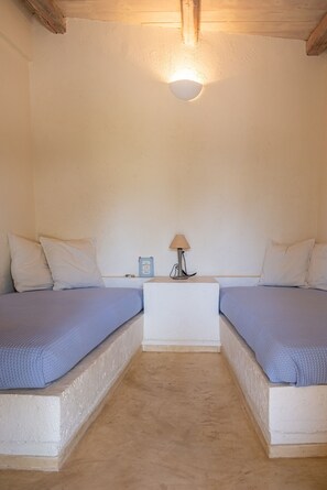 A room with two beds, a nightstand, a lamp, and a wall-mounted light fixture. - Zephyros Pool Tennis (Kea)
