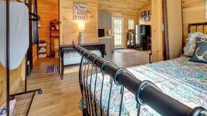Interior de una cabaña de madera con cama, escritorio, silla, televisor y un cartel que dice 'Relax you're on Lake Time'.