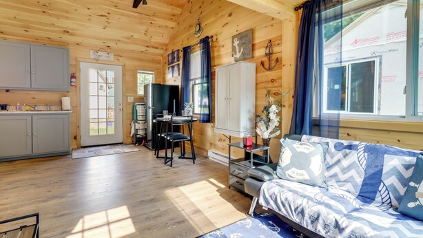Interior de una cabaña con kitchenette, comedor y sofá con ropa de cama de temática náutica.