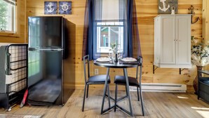 Una cocina compacta con refrigerador, una mesa de comedor con sillas y un armario.