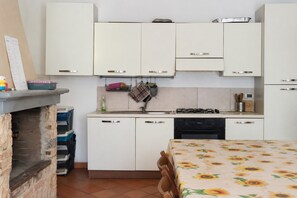 Una cocina compacta con muebles blancos, estufa a gas y lavamanos.