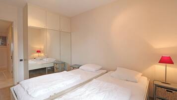 Une chambre à coucher comprenant un lit, une table de chevet, une lampe, une armoire et un miroir.